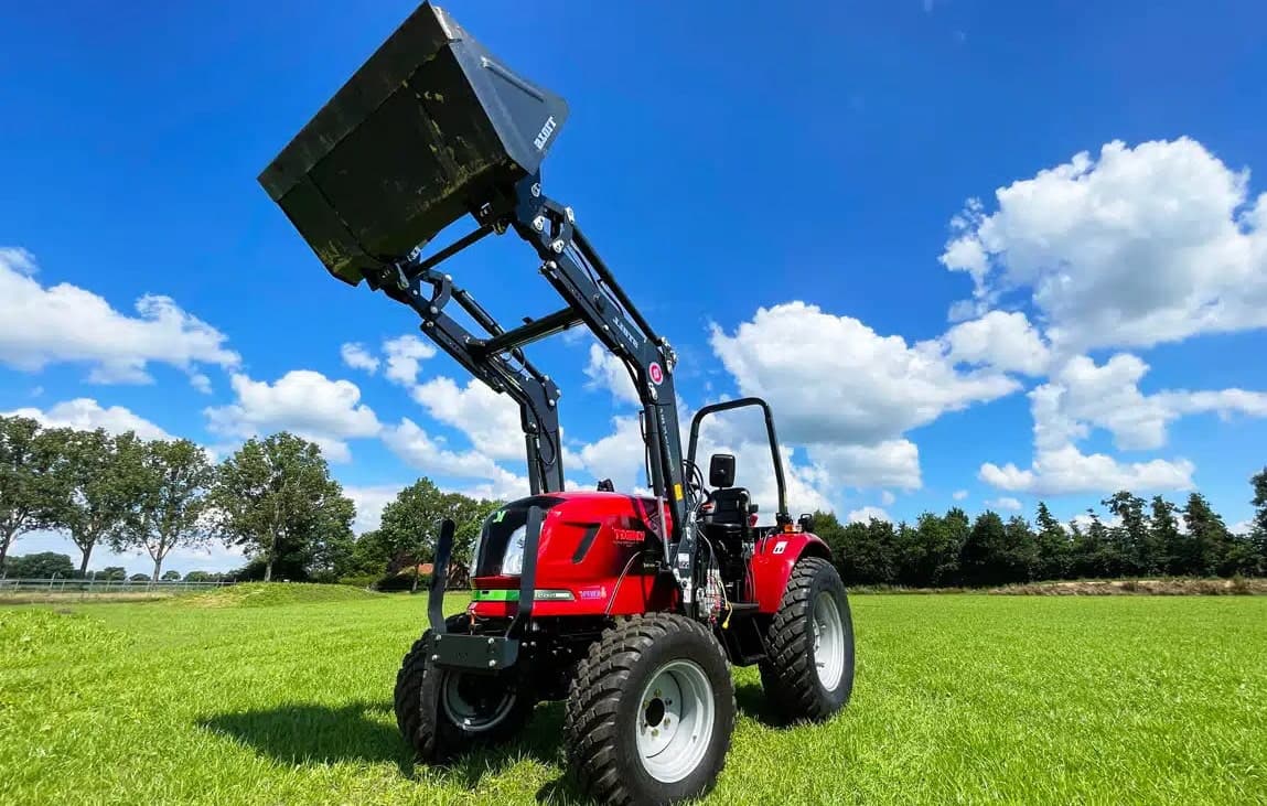 Electric tractor with front loader on grass